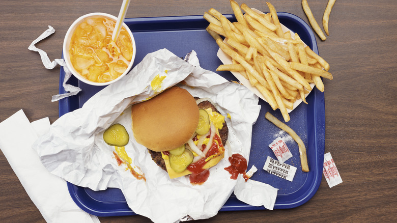 Top view of fast food burger, fries, and soda on blue tray
