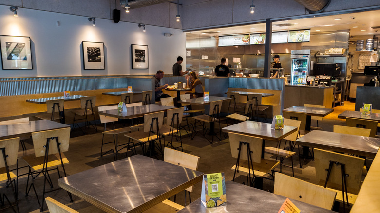 Interior of a Chipotle restaurant with customers at the counter and two seated.
