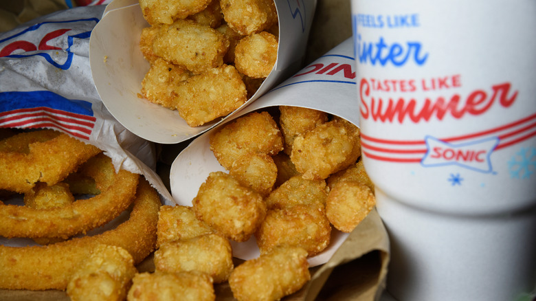 Sonic onion rings, tater tots, and a beverage on a tray,.