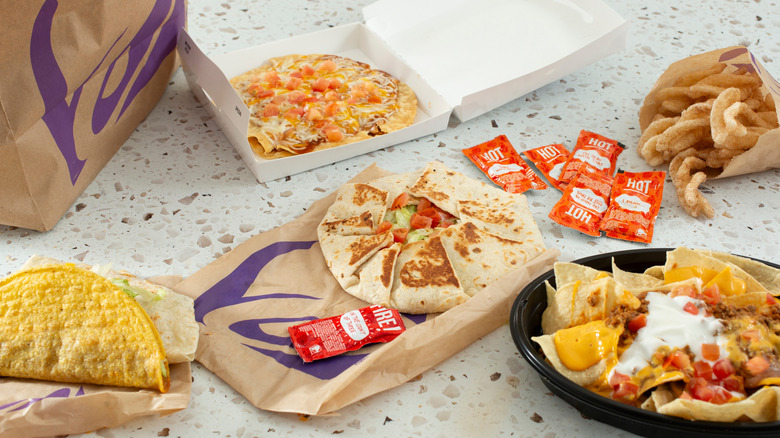 A Taco Bell hard taco, Mexican pizza, quesadilla, nachos, and cinnamon twists on a table.