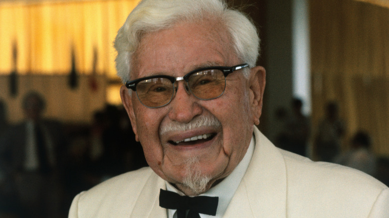 KFC founder Colonel Harland Sanders smiles in white suit and black bowtie
