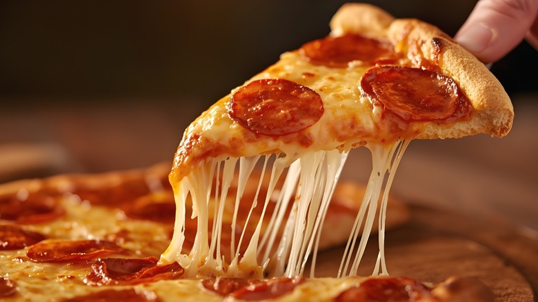 A slice of pepperoni pizza being separated from its pie.