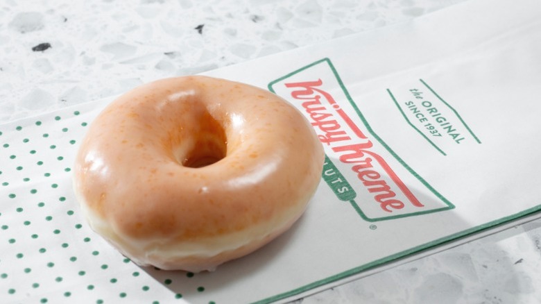 A Krispy Kreme glazed donut on a branded wrapper.