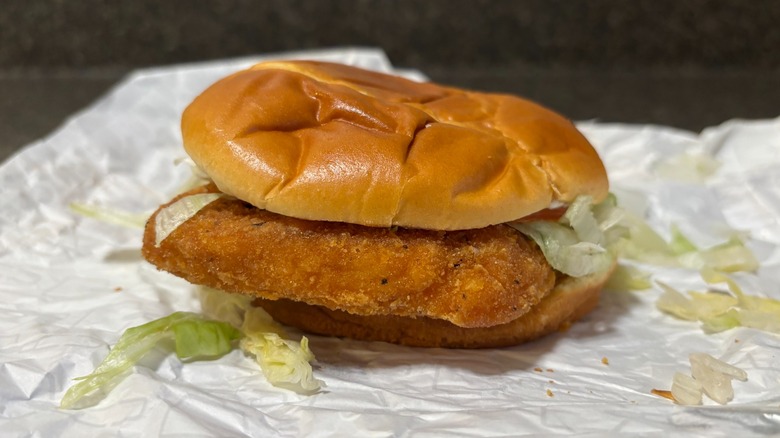 A fast food spicy chicken patty sandwich with lettuc on bun on wrapper