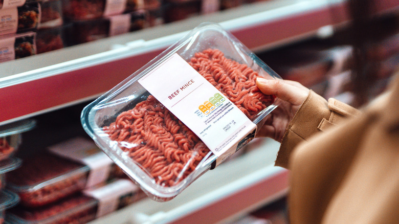 person looking at ground beef in the supermarket