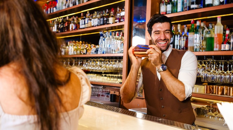 A bartender smiles while shaking a cocktail