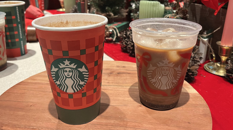 Starbucks holiday cups in front of a holiday-themed background