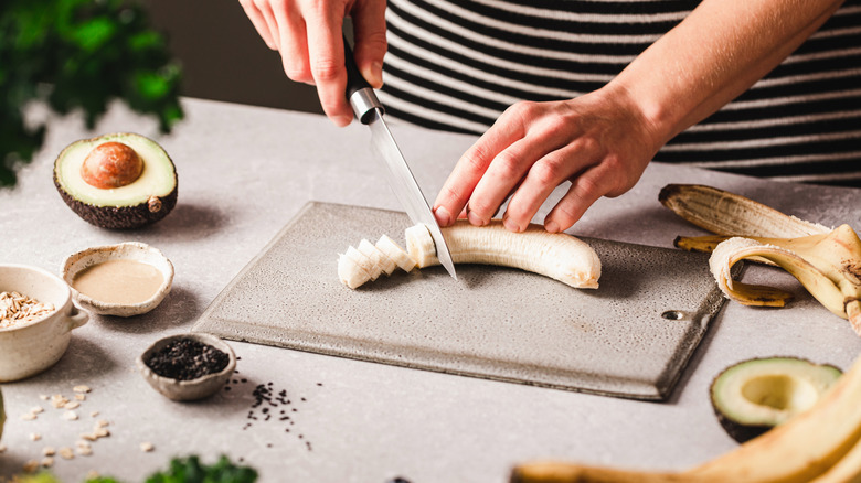 Close-up of a woman cutting banana on chopping board