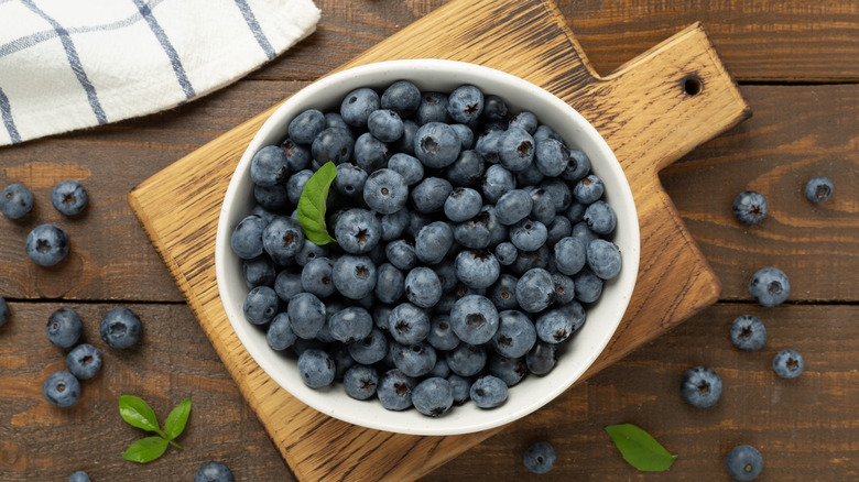 Bowl with fresh bright blueberries on wooden background,top view