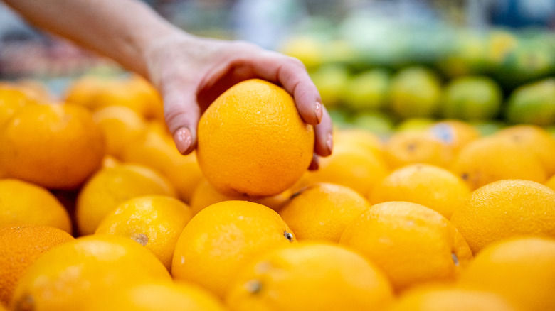 Close-up of woman's hand picking an orange in the supermarket