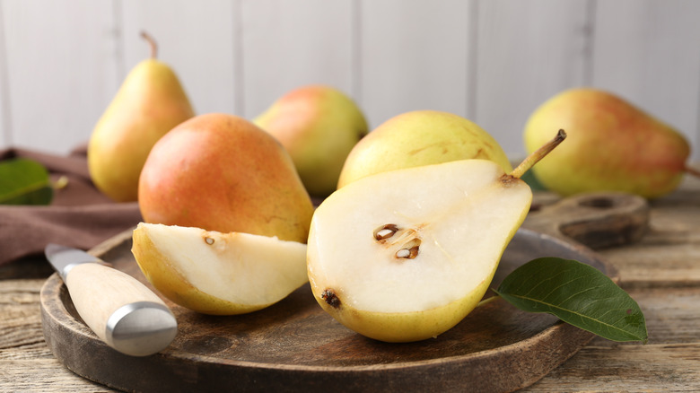 Fresh ripe pears and knife on wooden table, closeup