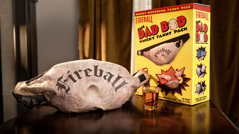 Fireball's Dad Bod Whisky Fanny Pack next to the box it comes in and a shot of Fireball