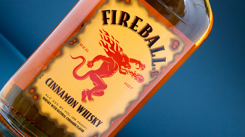 A bottle of Fireball Cinnamon Whisky in front of a blue background