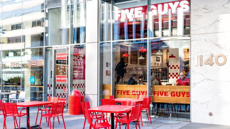 Five Guys restaurant view from outside, with orange tables on a patio.