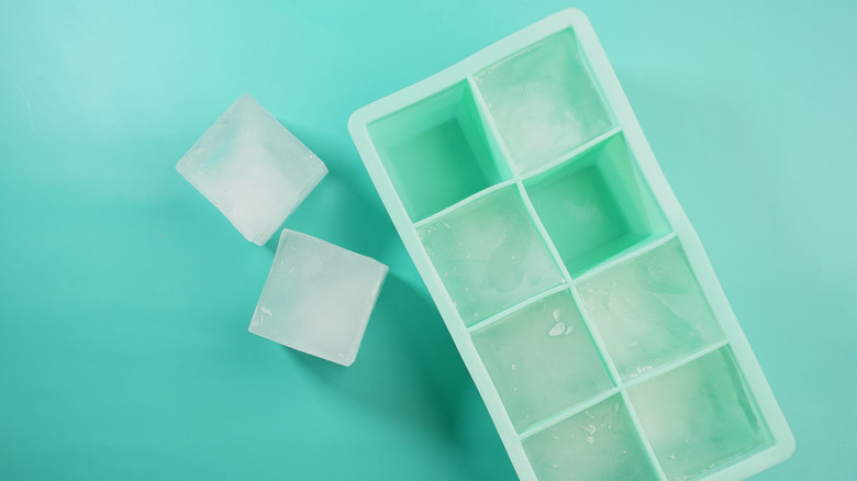 A silicone ice cube tray on teal background