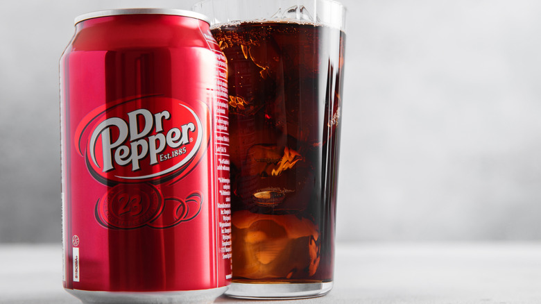 A can of Dr Pepper next to a glass of soda.