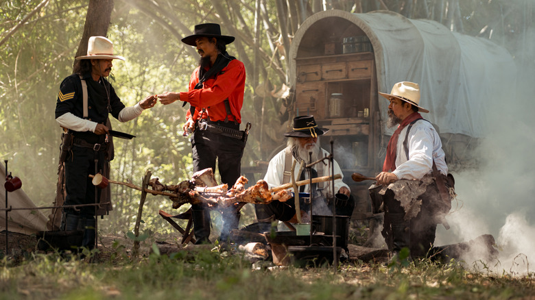 Reenactors sharing a meal by a chuckwagon over a fire