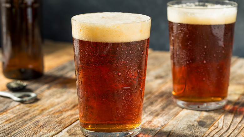 Two glasses of craft beer in pint glasses on a wooden tabletop
