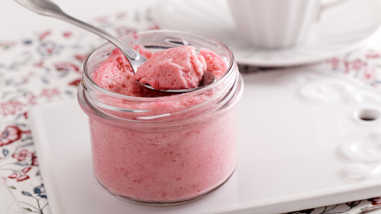 Glass jar and spoon with pink mousse dessert