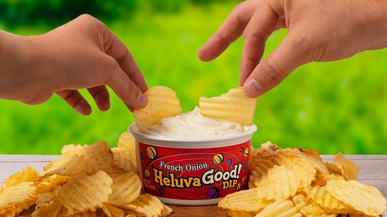 two hands about to dip a chip into Heluva Good! dip