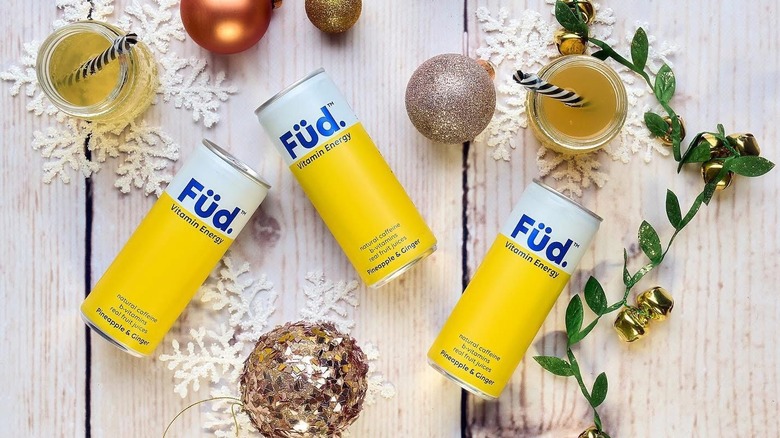 Füd cans on a table with ornaments and drinks around.