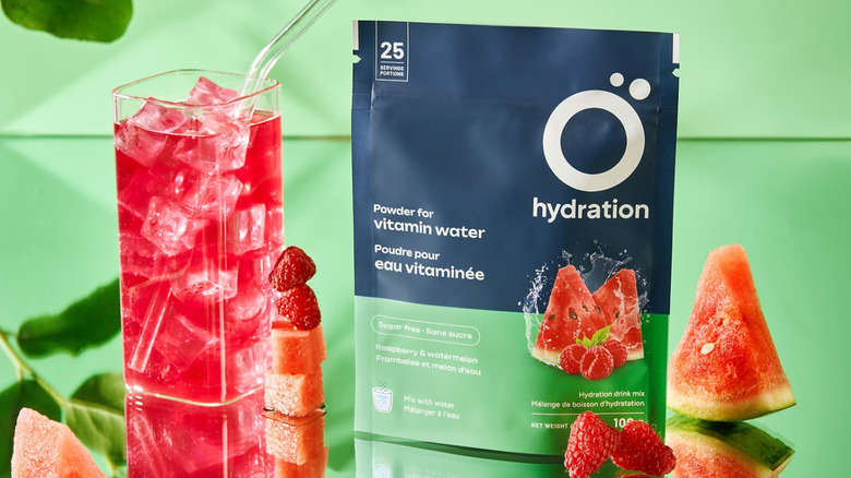 Ö Hydration package and pink drink with strawberries and watermelon pieces around.