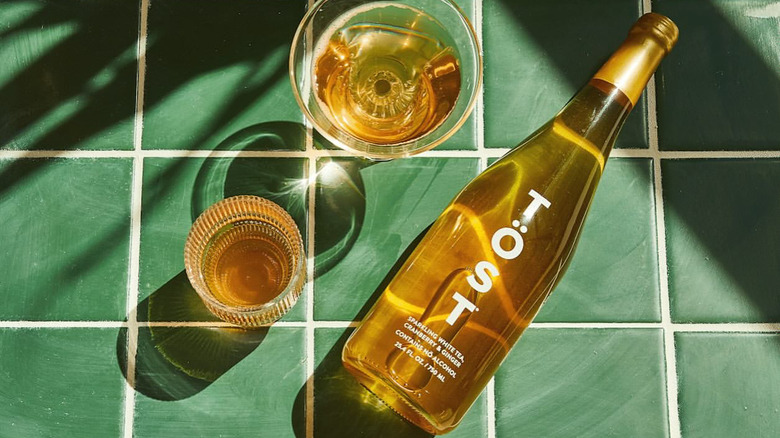 TÖST bottle of wine next to glasses on a sea green tile backdrop.