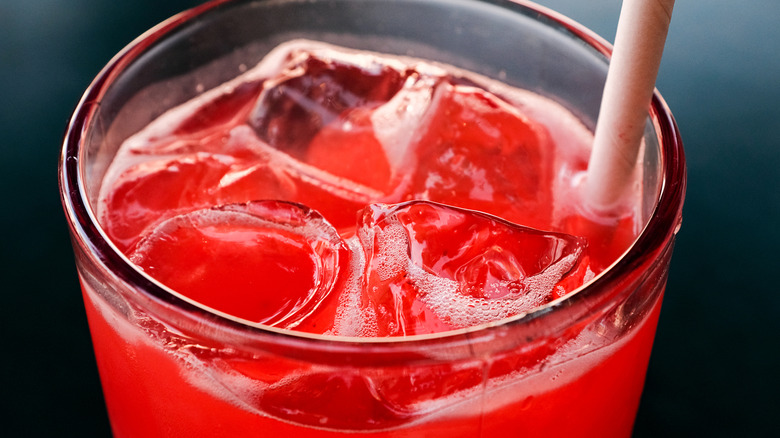 Bright red drink in glass with straw