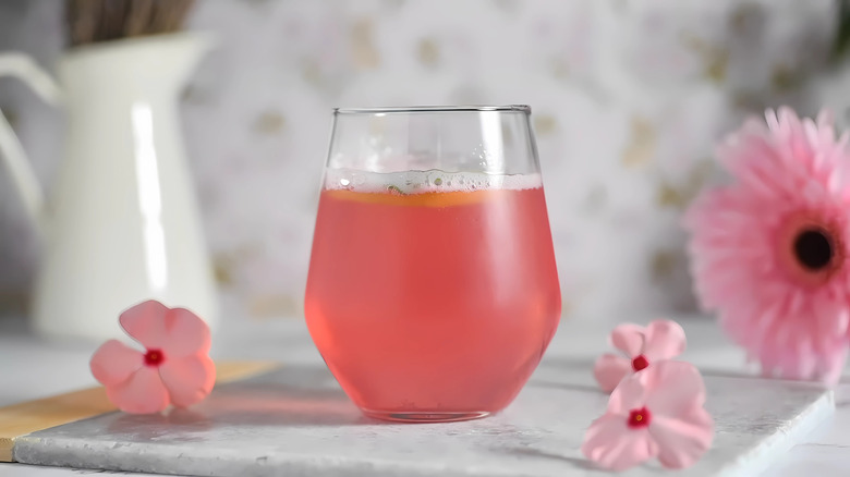 Glass of pink lemonade on a table with pink flowers