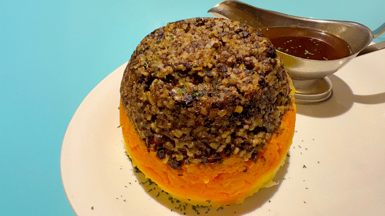 Traditional haggis on a plate with a gravy boat with sauce
