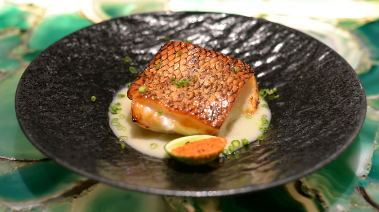 Chilean sea bass filet on black plate