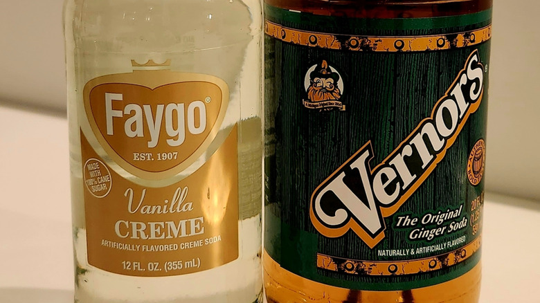 A bottle of creme soda next to a bottle of ginger ale