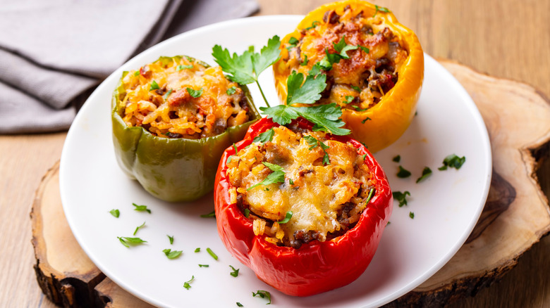 Red, green, and yellow stuffed peppers on white plate
