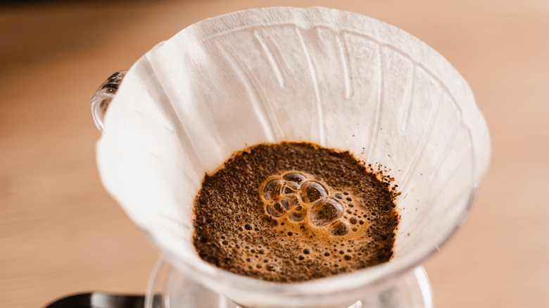 coffee in pour over pot with filter and grounds