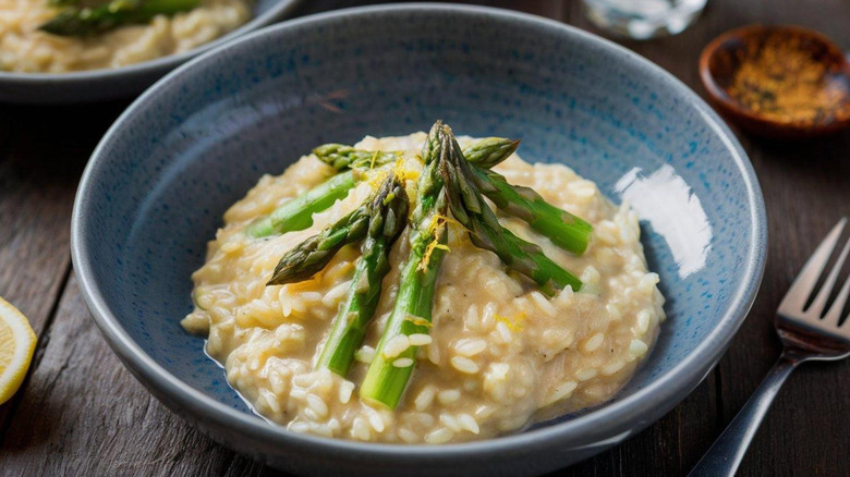 Creamy risotto with lemon zest and asparagus in blue bowl