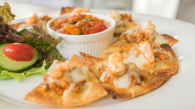Close up of pork and shrimp nachos served on a white plate.