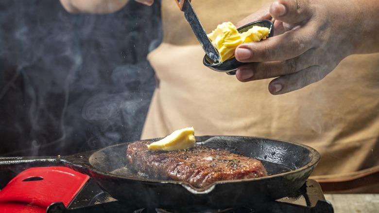 A home chef cooks a steak in a pan with butter