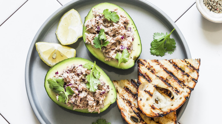 Tuna stuffed avocado - delicious healthy breakfast, snack, appetizer on a light background, top view