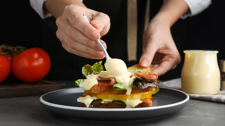 Woman placing mayo on a sandwich