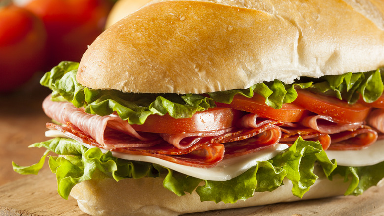A fresh Italian sub sandwich seen up close with lettuce, tomato, cheese, and meat.