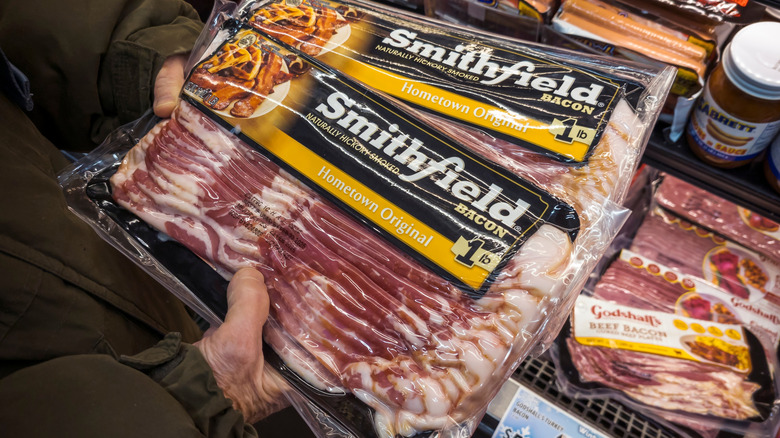 Hands holding packages of Smithfield bacon