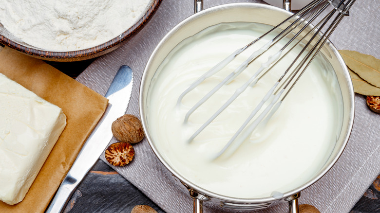 Whisk inside pot of bechamel sauce with whole nutmeg around it