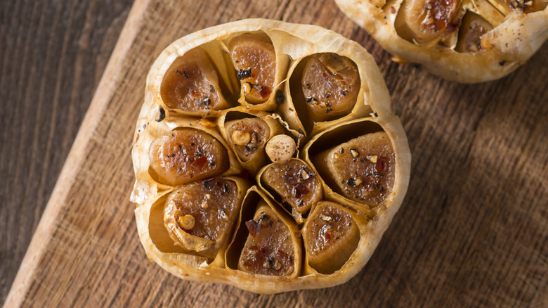 Top view of head of roasted garlic on wooden cutting board
