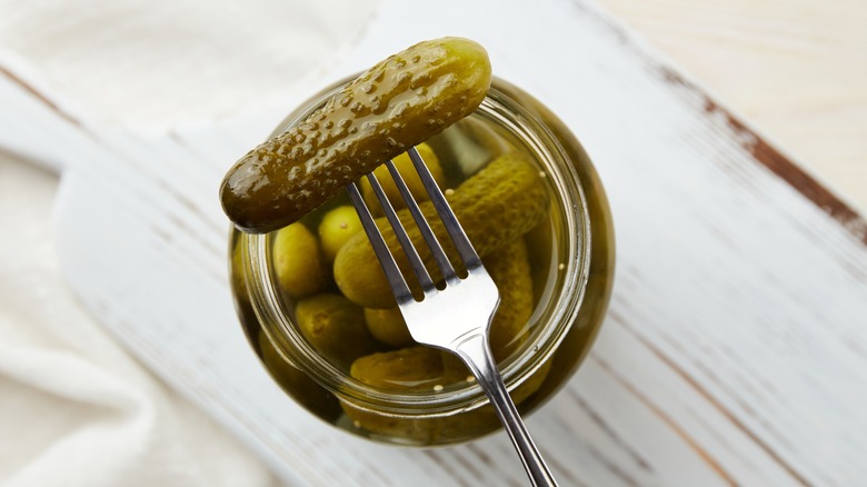 Top view of jar of pickles with fork spearing one