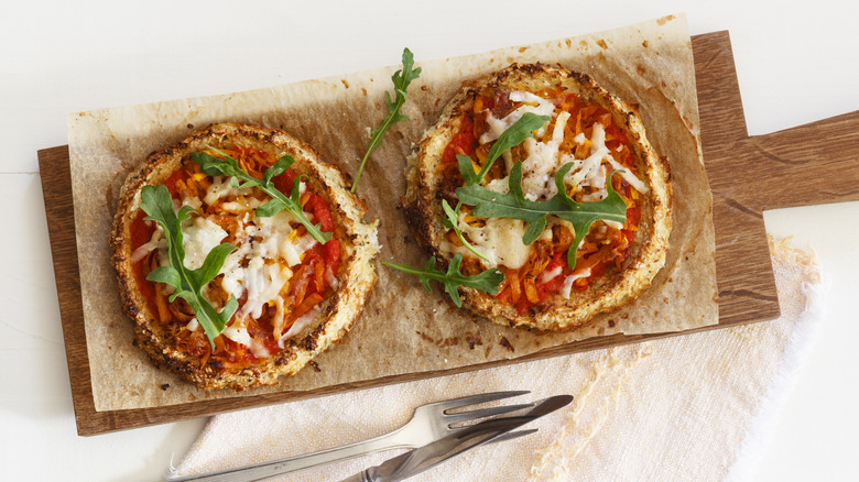 Two pizzas with gluten-free crusts on a wooden board