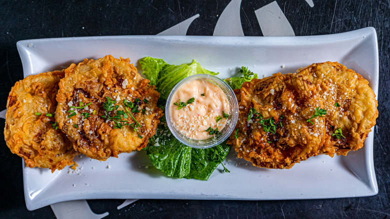 An overhead shot of a plate of fried green tomatoes with a creamy dipping sauce
