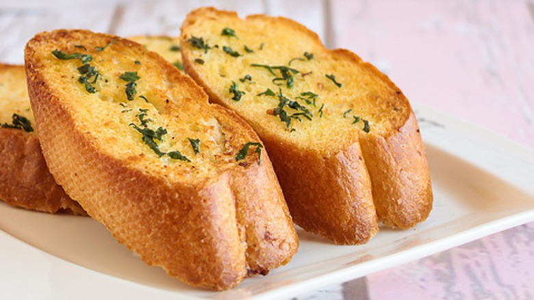 Slices of crispy garlic bread on a white plate.