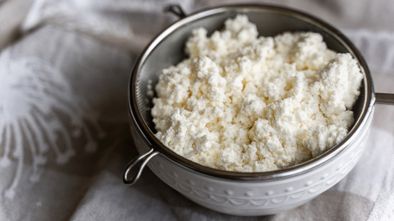 Ricotta in a strainer over a white bowl