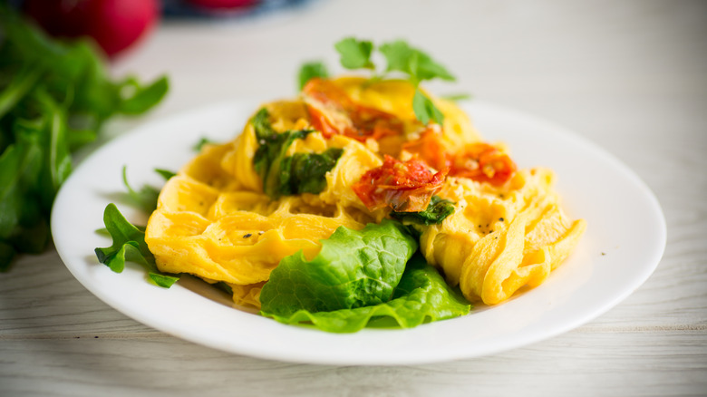 Omelet made in a waffle iron on a plate with vegetables