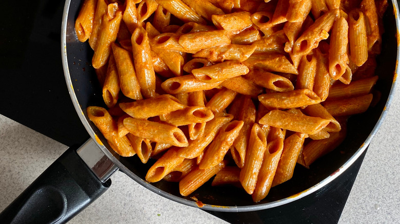 Penne alla vodka cooking in a black pan
